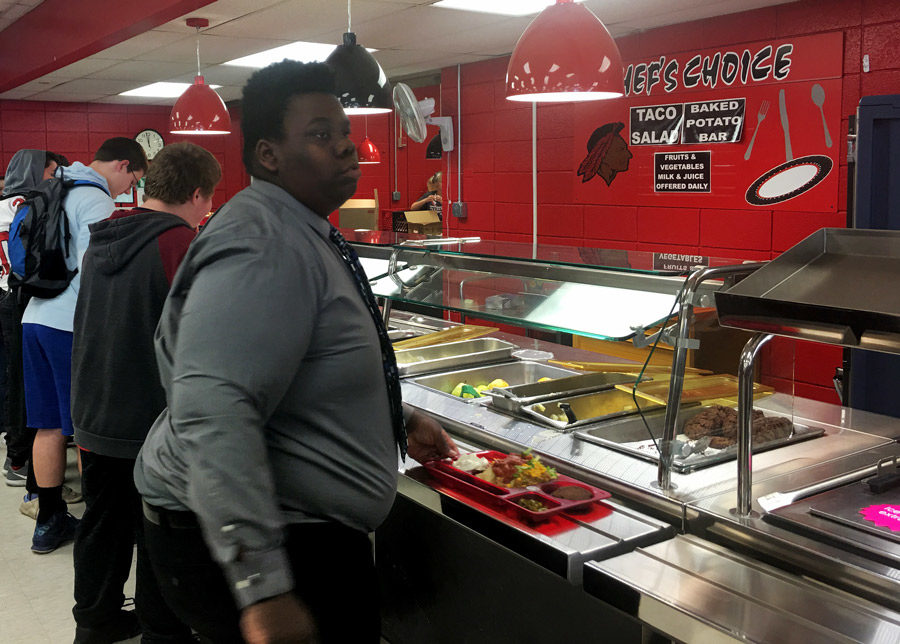 Junior Mylan Harris looks over the food items in the newly organized food station. The cafe started offering different options in the food lines at the start of November.