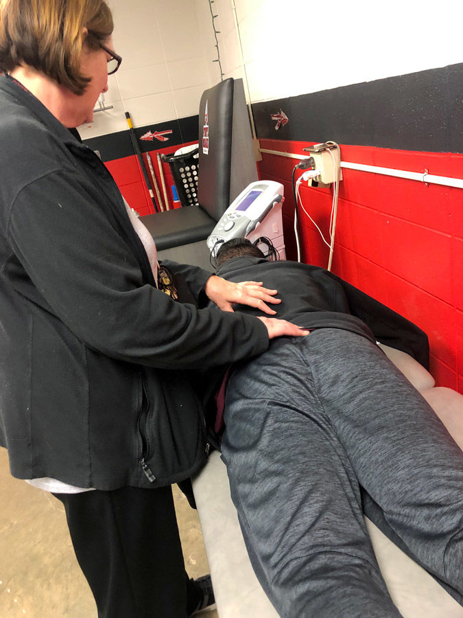 Utilizing the new training tables, Head Athletic Trainer Dawna Gilbert helps a student. The new training tables have been in use since the summer of 2018.