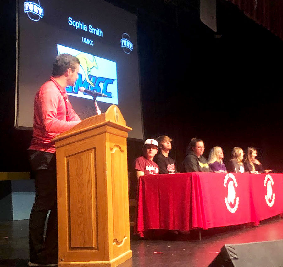 Addressing the crowd, Head Girls Soccer Coach Michael Brown talks about senior soccer player Sophia Smith (Far Right) and her commitment to play at UMKC. The other signees included (L-R) seniors Ethan Gotch (Baseball - Fort Scott  CC), Micah Copeland (Baseball - MO Valley), Mallory Huber (MO Southern State), Tess Kinne (MO Valley) and Lainey Camerlynck (MO Baptist U).