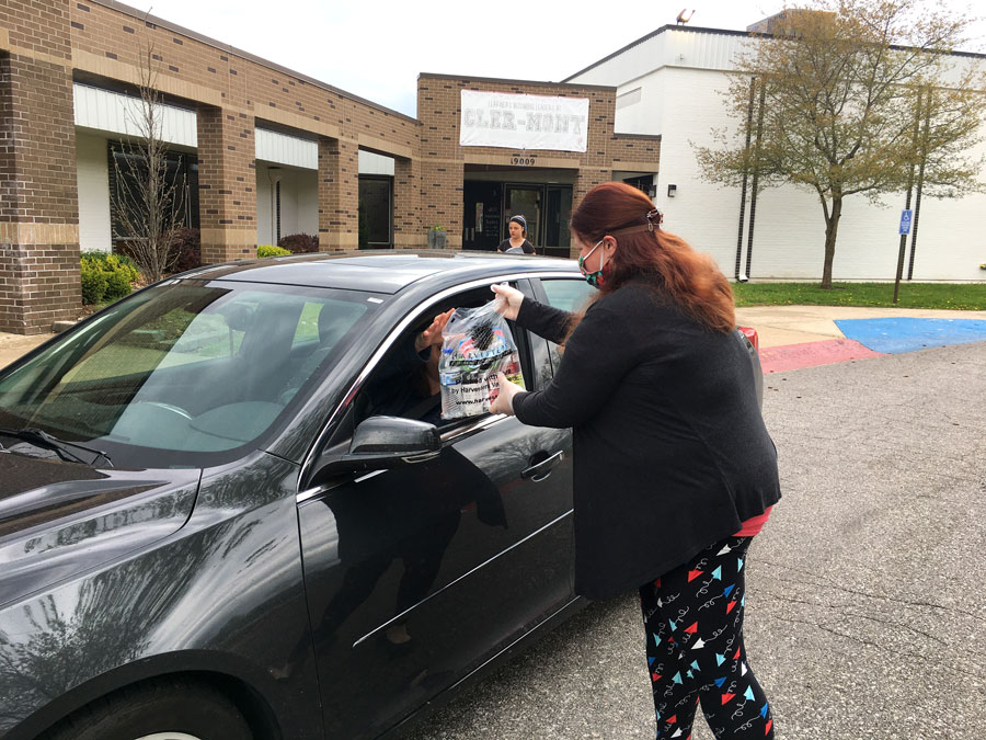 Meeting at a car, OTMS Teacher Ms. Allison Friedrich hands lunches to Ms. Susan Panther at Cler-Mont Elementary School. The district continues to deliver lunches for children 18 and under on Mondays and Thursdays at Cler-Mont Elementary, Blue Hills Elementary, Buckner Elementary, Elm Grove Elementary and Hawthorn.