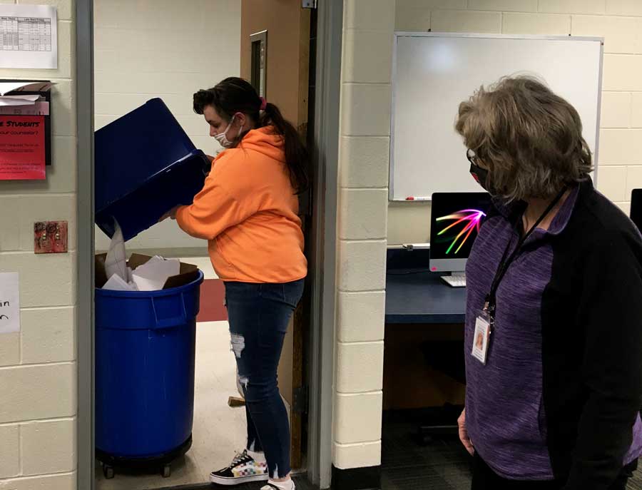 RECYCLING RESUMES. Making the rounds, Junior Kelsey Farrar dumps a recycling tub into a collection can on a recent Friday under the supervision of Special Education Para Delana Jones. The Job Skills class resumed recycling efforts earlier this semester.