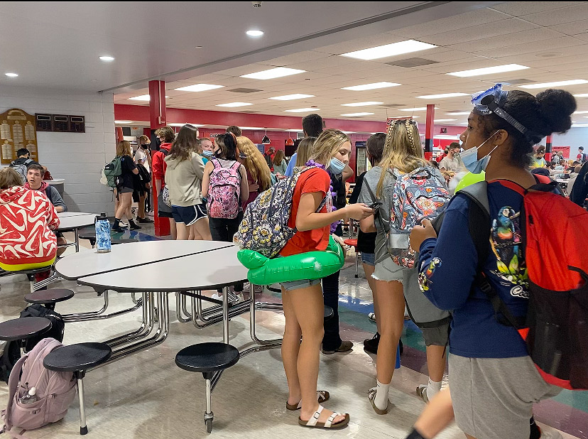 WAITING. Keeping busy, students check their phones and visit while waiting in the unusually long lunch lines. The school year started with increased congestion due in part to a change from six lunch shifts to four lunch shifts.