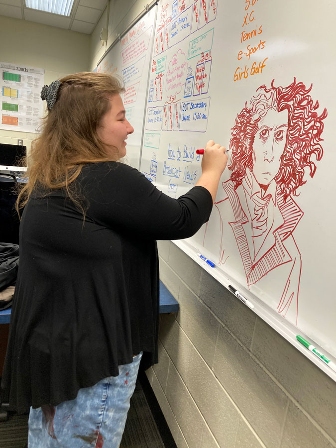 WHITEBOARD+DOODLE.+Robin+Nichols+draws+a+character+on+the+whiteboard+during+her+Advisory+class.++She+has+left+a+drawing+every+Advisory+period+for+students+to+enjoy.+%E2%80%9CMy+favorite+things+to+draw+are+people+because+of+how+different+each+one+is%2C%E2%80%9D+Nichols+said.