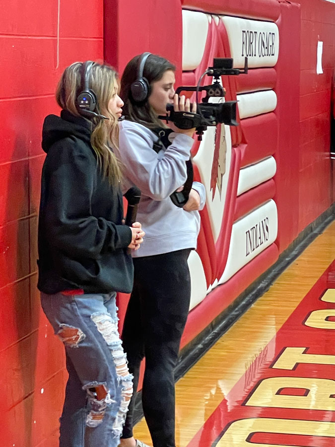 SIDELINE REPORTING.  Senior Taryn Sinthusy (L) is observing and reporting with camera operator Junior Peyton Ramirez (R) during a basketball game. Sinthusy spent all four years of high school participating in the broadcast program. “I love talking about football because it’s so exciting and our football team is really good,” Sinthusy said.