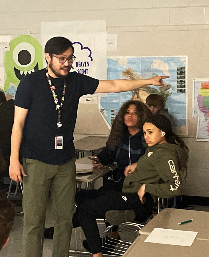 PASSION. Mr. Rayn Tupinio(L) explains the rules to an educational game as students Kylie Corum (R), Ayden Vaeao (Middle), and Jax Navarro (Back) listen. Mr. Tupinio has been utilizing games to educate students since he began teaching, but has been putting more focus on them this year. “I try to build things into my class that keep students interested,” Tupinio said. “Whether that be building more perspectives into my teaching or through the games that we’ve been playing.”