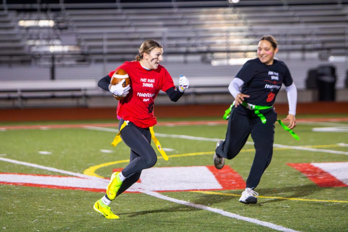 POWDER-PUFF. Junior McKenna Simons rushes down the field towards the end zone while senior Kyli Bisbee is hot pursuit. Seniors had half the amount of players as the juniors and were still able to pull off a win.  “Most of my friends are seniors,” Simons said. “It was really fun to compete against my older friends.”
